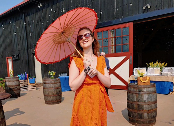 Photo of Emma Farnham in an orange dress holding an umbrella