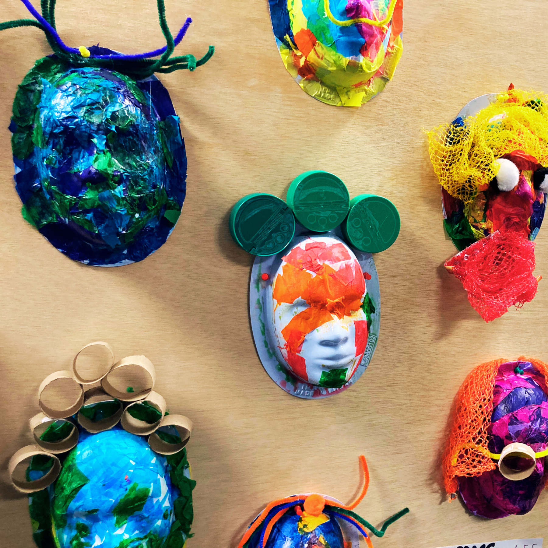 CASH a photo of a wall with student- made colorful masks hanging on it