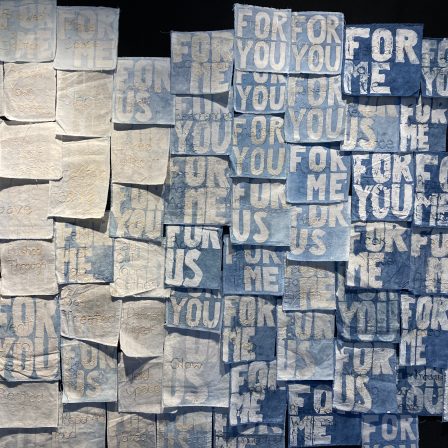 Fabric squares dyed with Indigo against a felt wall. Dyed into the squares is the text "For Me", "For You", or "For Us".