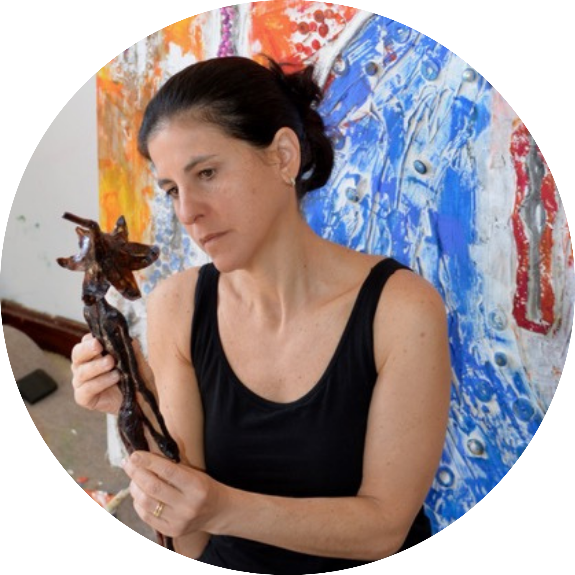 5 (1) a photo of Silvina Mizrahi, a light skinned latina woman with dark hair pulled back, holding a piece of artwork and gazing at it